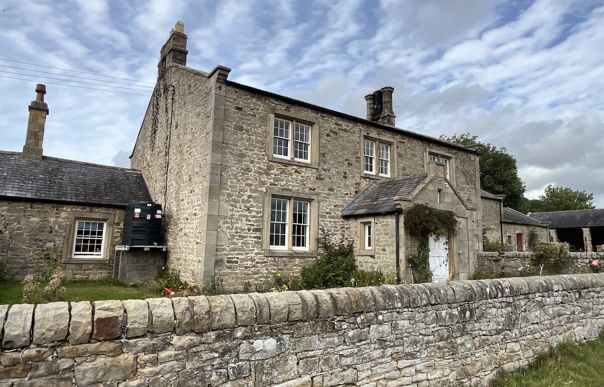 Existing stone farmhouse and outbuildings behind a dry stone wall