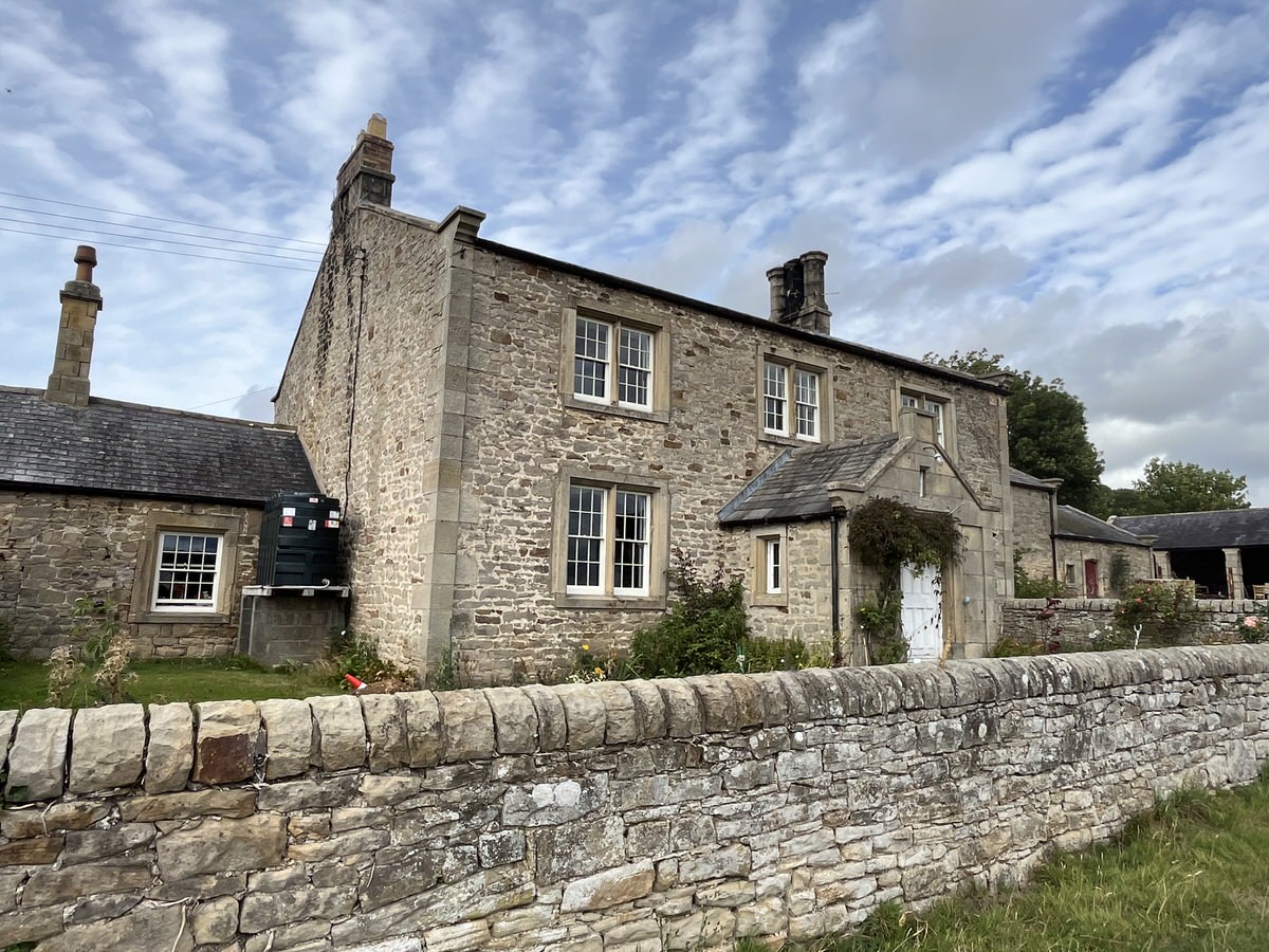 Existing stone farmhouse and outbuildings behind a dry stone wall