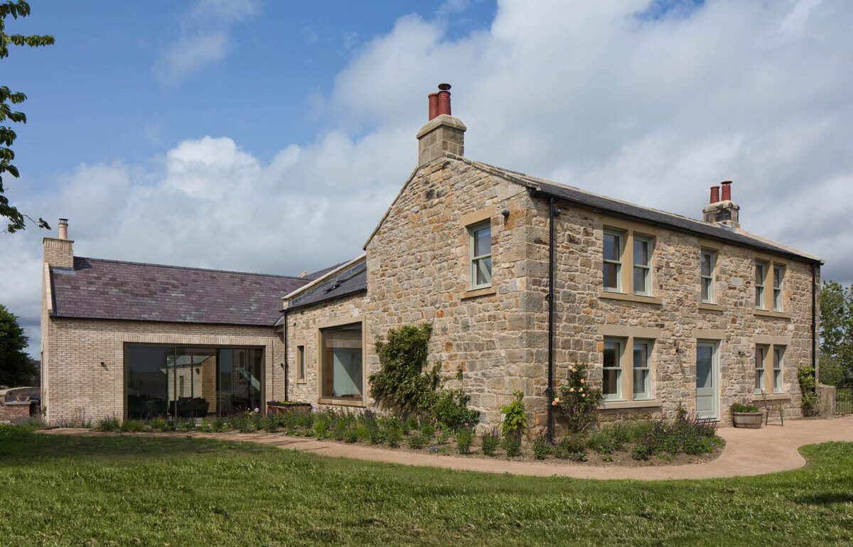 Restored stone farmhouse with a modern single-storey extension and gravel path
