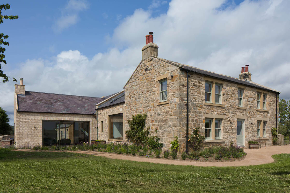 Restored stone farmhouse with a modern single-storey extension and gravel path