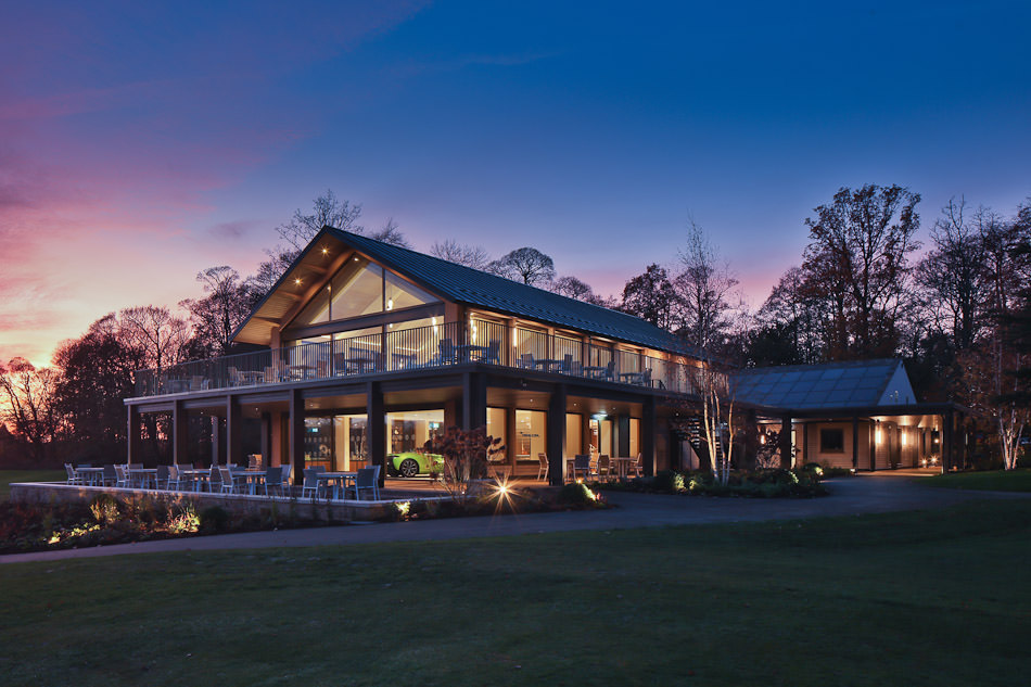 Golf clubhouse with a glazed gable and balcony lit at sunset